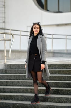 Young woman in spring-autumn casual outfit descending the stairs outdoor