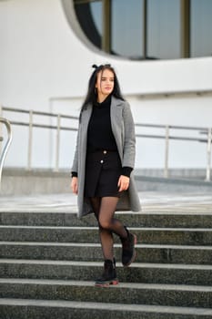 Young woman in spring-autumn casual outfit descending the stairs outdoor