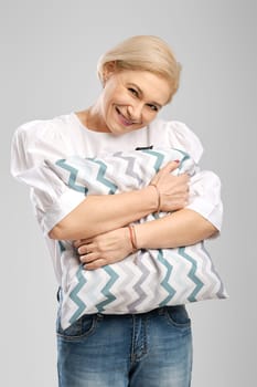 Happy smiling senior woman hugging soft pillow