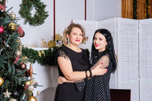 Middle age mother hugs her daughter celebrating christmas together. Family relations concept.