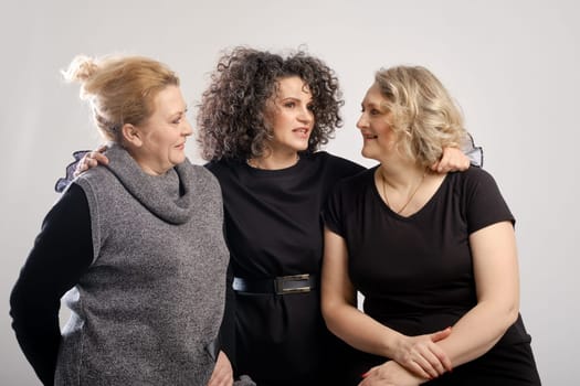 Three cheerful middle aged women friends discussing news or gossip (studio photo)