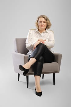 Full body studio portrait ofconfident senior woman in white shirt with crossed arms