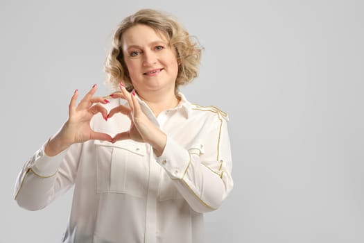 Happy senior woman shows love gesture. Middle aged woman folded palms of her hands in the shape of a heart.
