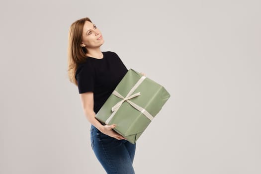 Young woman posing with large gift box over grey background