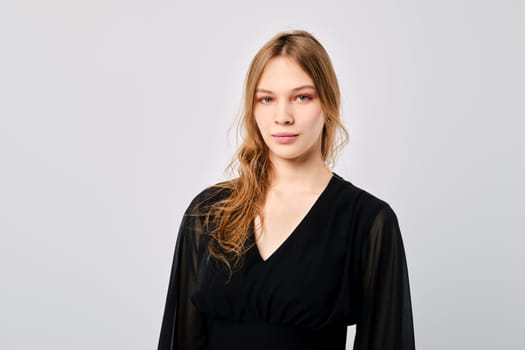 Studio portrait of calm and positive young woman looking straight over grey background