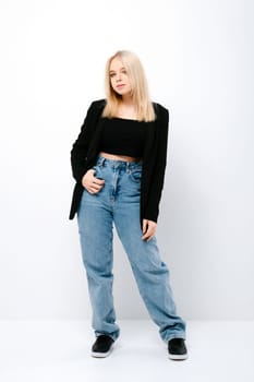 Blonde girl in tank black top, jacket and jeans posing