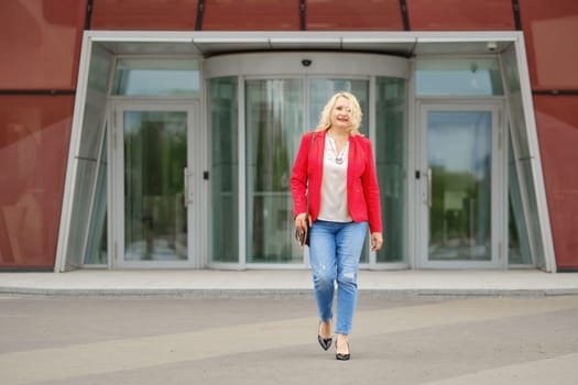 Satisfied middle age woman walks out the bank or office building, she is full of hopes and expectations