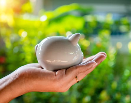 Hand human and Piggy bank on natural bokeh background. saving concept