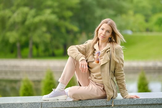 Sportive middle aged woman sitting on an embankment