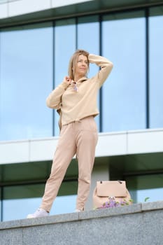 Sportive middle-aged woman looks into the distance and straightens her wind-blown hair