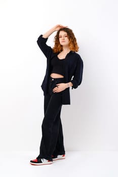 Young teenager model in black trousers and shirt posing over white background