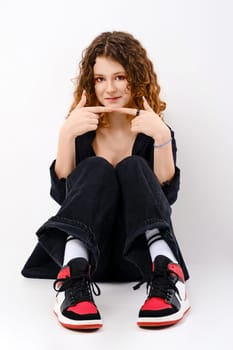 Lovely teenager girl sits on the floor and touching her fingertips