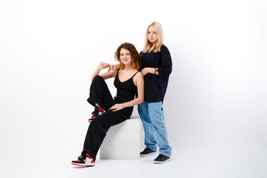 Two positive and funny teen girls together over white studio background