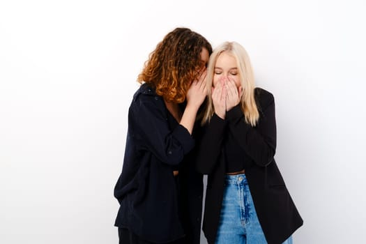 Two young teenager girls gossip and laugh over white background