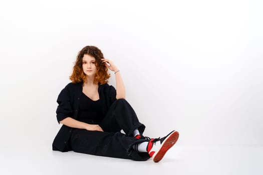 Teenager girl with colored hair sitting on the floor in white studio