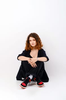 Cute girl sitting in studio on the floor with crossed legs