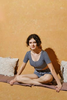Pretty young girl sits cross-legged on stone bench in sunny day