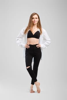Full length studio portrait of young barefoot woman in black jean and shirt