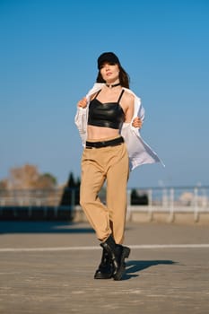Street fashion, women casual and trendy outfit. Woman in pantsuit, leather tank-top and rough boots outdoor.