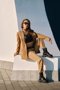 Street fashion, women casual and trendy outfit. Woman in pantsuit, leather tank-top and rough boots outdoor.