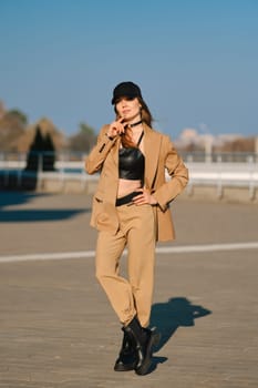 Street fashion, women casual and trendy outfit. Woman in pantsuit, leather tank-top and rough boots outdoor.