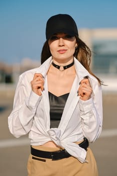 Street fashion, women casual and trendy outfit. Woman in pantsuit, leather tank-top and rough boots outdoor.