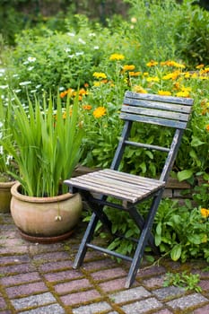 wild garden - herb spiral in the garden with fresh herbs and flowers and old chair