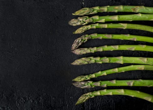Top view of fresh green asparagus on rustic black board with copyspace. Food and cooking recipe background.