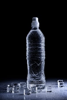 Fresh drinking mineral water in plastic bottle on black background. Healthy living concept.