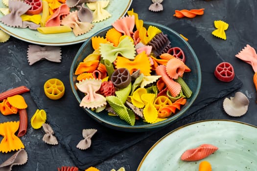Colorful italian raw pasta on plate. Heap of colorful macaroni