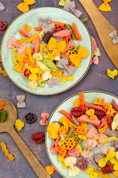 Colorful italian raw pasta on plate. Heap of colorful macaroni