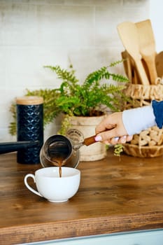 Closeup view of hand pouring coffee in a cup. Morning routine concept.