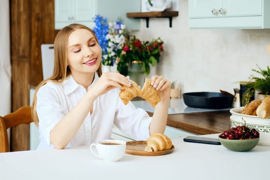 Cute young woman tears apart a fresh croissant