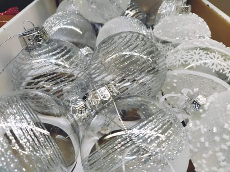 Large transparent beautiful Christmas balls in a box on a shelf in a store. Sale of Christmas New Year's toys and decorations before the holiday. Glass Christmas decorations