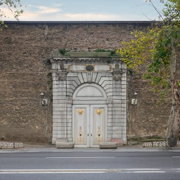 White wooden arched decorated door, framed by white marble decorations, in a stone brick wall, Ciragan Street, Istanbul, Turkey