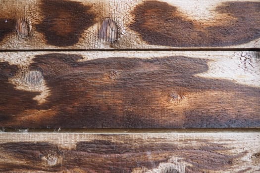 Burnt scorched horizontal boards background. Wooden background close-up with black burnt spots