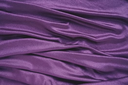 Velour fabric, similar to silk. Textiles in a folds and beautiful waves. Purple, pink, magenta shades on the drapery. Sewing material for evening dresses, furniture upholstery, curtains and interior