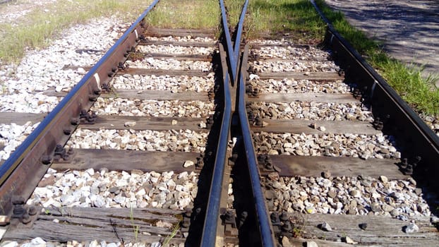 railways. Rails and sleepers on the ground near the station. Long way concept. Interlacing of tracks, railway arrows. Change of direction. Metal heavy rails.