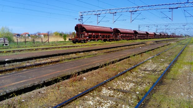 Sremska Mitrovica, Serbia, June 1, 2020. Freight wagons at the railway station. Lots of rails and sleepers, blue sky in the background. Early summer.