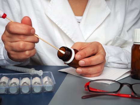 test in the hands of a doctor. Doctor, nurse or laboratory assistant at work in the laboratory. On the table are glasses, measuring instruments, paper, medicines in bottles.