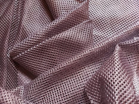 Synthetic polyester fabric with holes. Abstract background. Wave-folded pink fabric. Furniture upholstery.