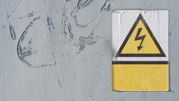 old danger sign with indication of high voltage on a door to an industrial building