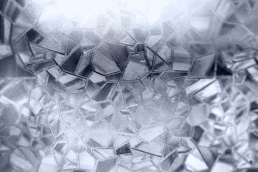 Embossed glass background. Corrugated glass monochrome. Refraction of light in a bumpy transparent surface under backlight. The play of white and gray highlights. Black areas. Abstract background