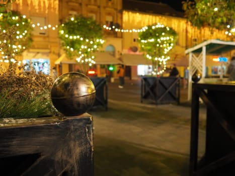 Hanging garlands against the background of the night sky. Festive decoration of city streets. Garlands of yellow, white and gold lights and bulbs. Beautiful background for New Year, Christmas holiday
