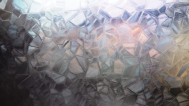 Fluted glass with backlight. Beautiful multicolored refraction of light. Abstract background. Self-adhesive film. Ribbed glass surface. Embossed glass background.