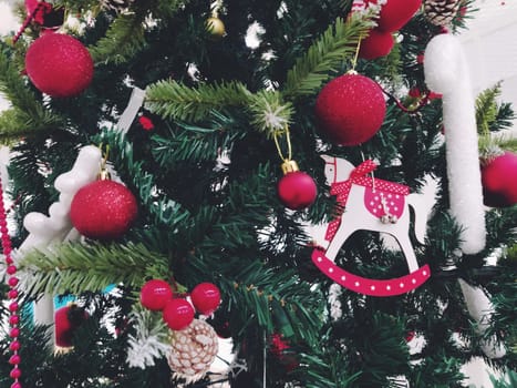 Christmas tree with decorations, Christmas balls and toys. Red and white hanging ornaments. Beautiful balls, bright berries and cones. Snow candy stick. Toy - rocking horse.