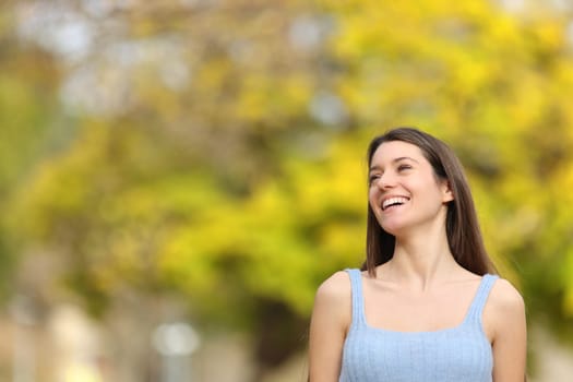 Happy teen laughing in a park looking at side