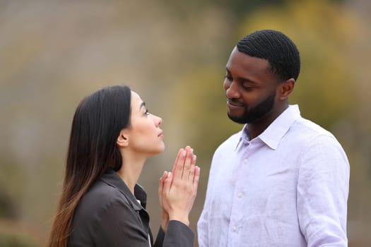 Woman begging forgive to a black man in a park