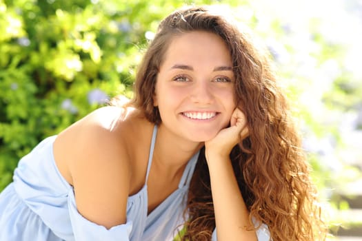 Happy beauty woman smiling at camera with perfect teeth sitting in a park