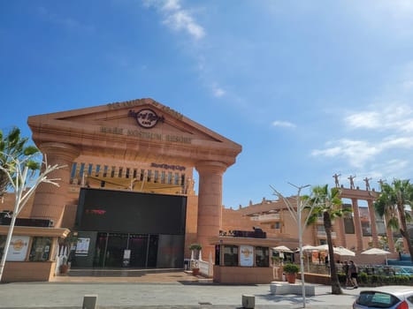 Hard Rock Cafe, Playa de la Americas, Tenerife, Spain August 12, 2022 - View from across the street of the Cafe building with palm trees and sky